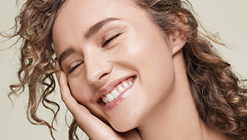 Fotografie asi dvacetileté smějící se ženy světlé pleti se zrzavými vlasy se zářící pletí