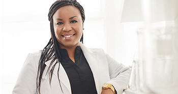 Fotografie Dr. Shoná Burkes-Henderson, vědecké pracovnice v klinickém výzkumu, vědkyně s tmavou pletí, usmívá se, prostředí navozuje atmosféru vědeckého výzkumu